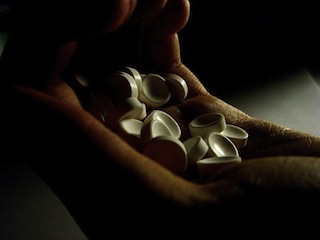 Photo of hand holding many white pills.