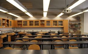 A medium-sized classroom with rows of tables and chairs.