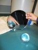 Photo of a student looking at a glass ball on a table with a round mirror.