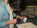 Photo of a student examining a round mirror on a table on which is placed a block and a smaller, upright mirrors.