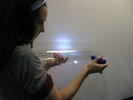 Photo of a student shining a flashlight through a grid on a curved piece of plastic.