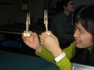 A student looks through two different lenses, held in clothespin supports.