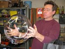 Photo of Peter Houk holding a glass sphere that he made.