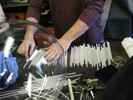Photo of artist Peter Houk laying out dozens of white glass rods on a table.