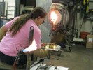 Photo of a glassblower working with hot glass.