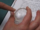 Photo of a lens held over a handwritten page.
