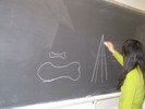 Photo of a student drawing Galileo's diagrams on the blackboard.