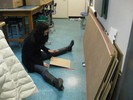 Photo of a student sitting on the floor and rolling a ball down a cardboard ramp.