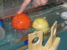 Photo of a student touching one of many colored balls made of various materials and sizes in an aquarium partially filled with water.