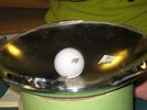 Photo of a golf ball rolling on a curved mirror surface.
