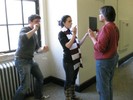 Photo of one student holding the mirror up for another student while the third looks at the mirror over her shoulder.
