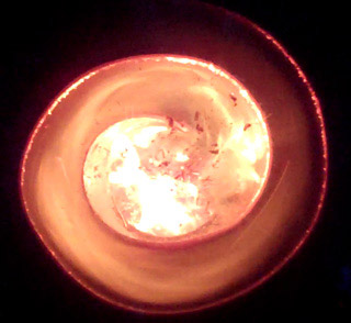 Photo of a metal spiral with flame traveling around it.