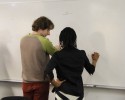 An instructor and a student work together at a whiteboard.