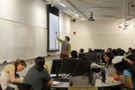 An instructor points at a slide on a projector screen as seated students look on.
