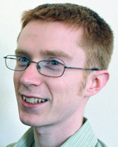 A headshot of a young man with red hair and glasses.