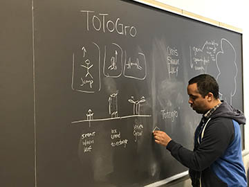 Student drawing videogame schematic diagram on chalkboard