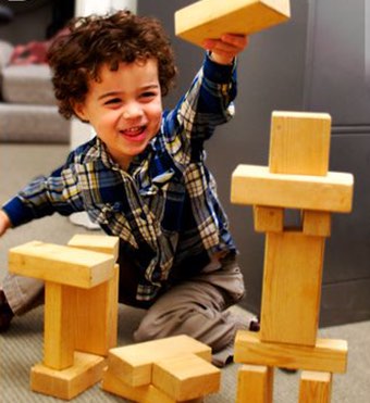 Photo of a young boy building a tower out of wooden blocks.