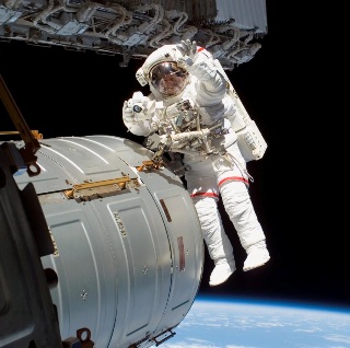 Photograph of astronaut outside space station.