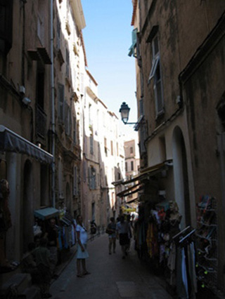 Photograph of a narrow, shaded street.