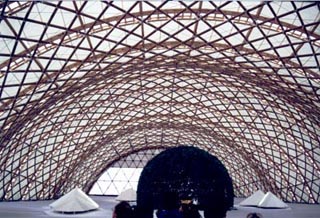 A photo of a large, arched metal superstructure above several geometric shapes.