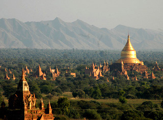 Photo showing many temples and stupas on a plain, with a mountain range in the background.