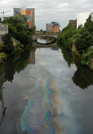 Photo of oil sheen on river going through city.