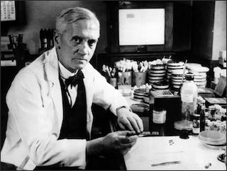 A black and white photo of Alexander Fleming in his laboratory.