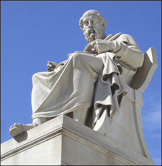 A white marble statue of Socrates in Athens, Greece in front of a clear blue sky.