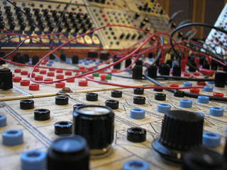 Closeup of knobs, dials and wires on an analog synthesizer.