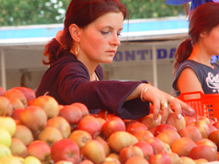 A woman selects apples at a fruit market.