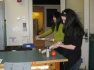 Photo of students rolling colored balls of various sizes in plastic and cardboard tubes.