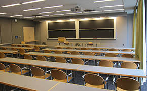 A typical classroom with rows of seats, as well as chalkboards and a projector screen at the front of the class.
