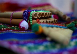 Photograph of a pan flute on a colorful blanket.