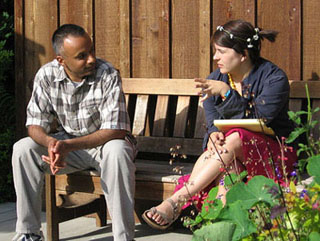 Man and woman sitting on a bench, talking. Woman is gesturing.