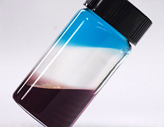 Photo of a vial containing three colored liquids in distinct layers.