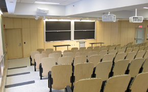A large classroom with tiered seating and several chalkboards.