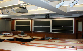 A large classroom with tiered seating and several blackboards.