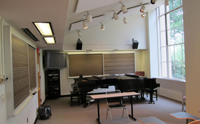 Photo shows the two pianos, blackboards that include staves, display, and audio components at the front of the classroom.