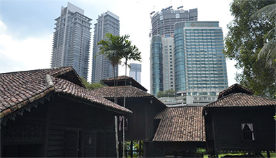 Wooden houses with tile roofs in the foreground; high-rises in the background.