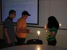 Students aim a mirror at a lit lightbulb.