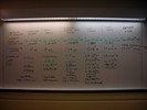 A whiteboard contains notes written in scientific notation.
