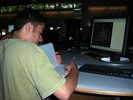 A student sits at a computer and writes observations in his notebook.