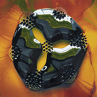 A greenish-black drop of liquid iron, sits on an orange background. 