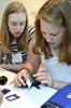 A photo of two girls taking apart a digital camera.