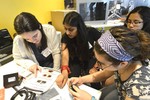A photo of a group of girls working on building a camera together.