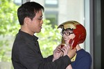 A photo of a man helping a woman put on an Iron Man mask.