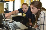 A photo of two girls working together at a laptop.