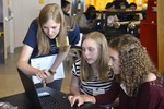 A photo of three girls working together at a laptop.