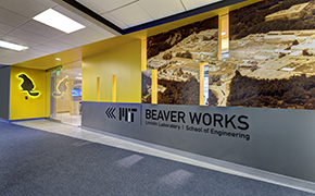 The entrance of MIT Beaver Works with the lighted beaver logo on the wall.